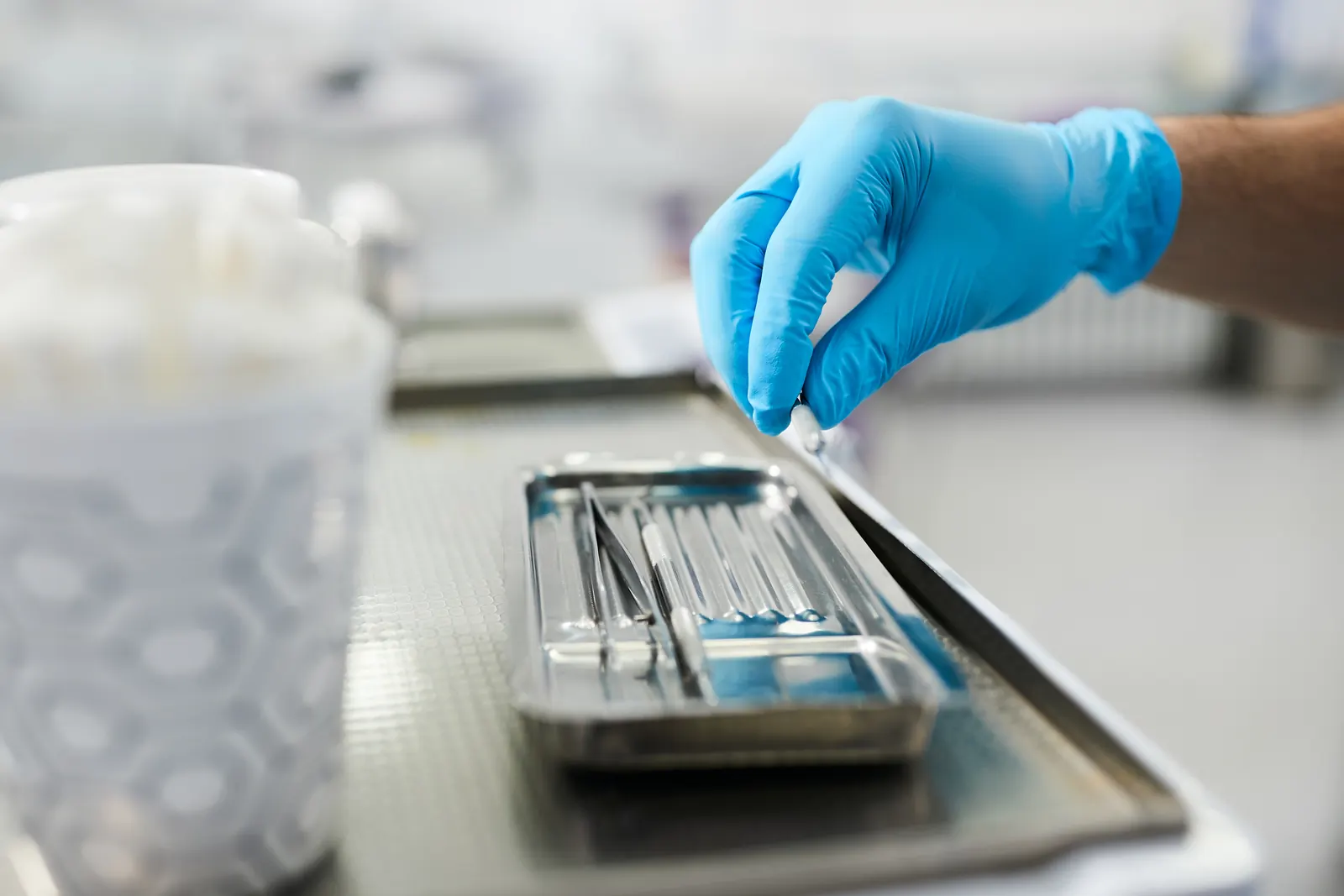 Gloved hand preparing sterile dental instruments